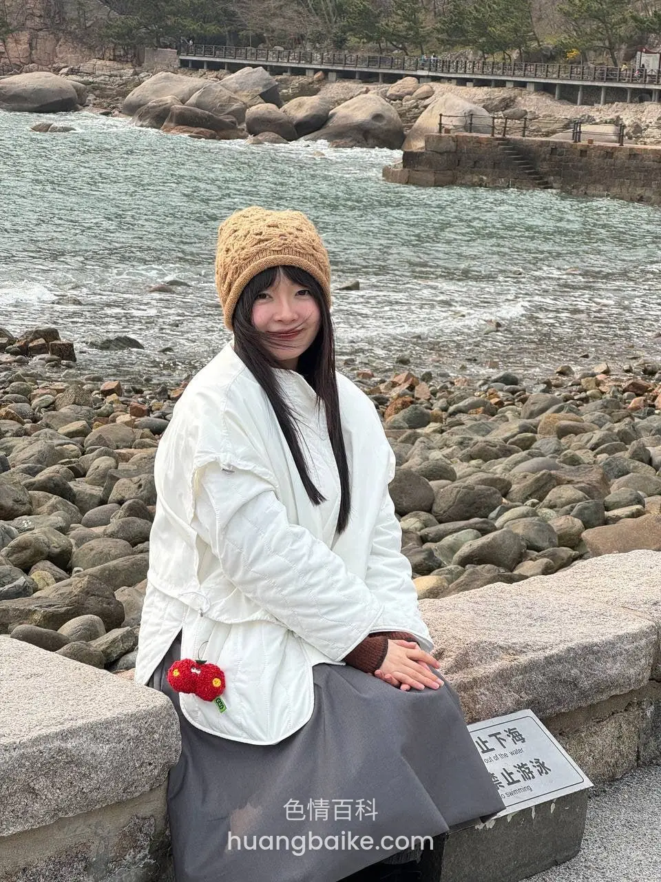 海边岩石上，旁边牌子写止滑止落冰