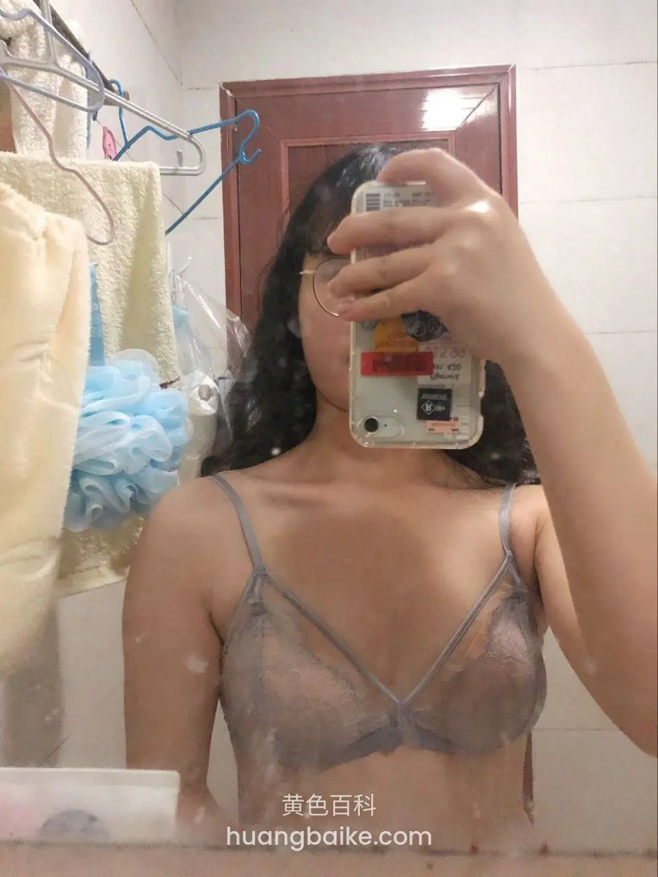 手机挡住脸拍镜子，身后挂着浴球