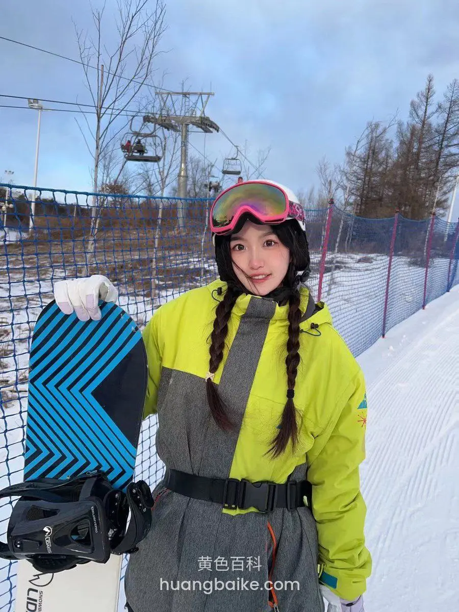 雪地里拿滑雪板，身后缆车