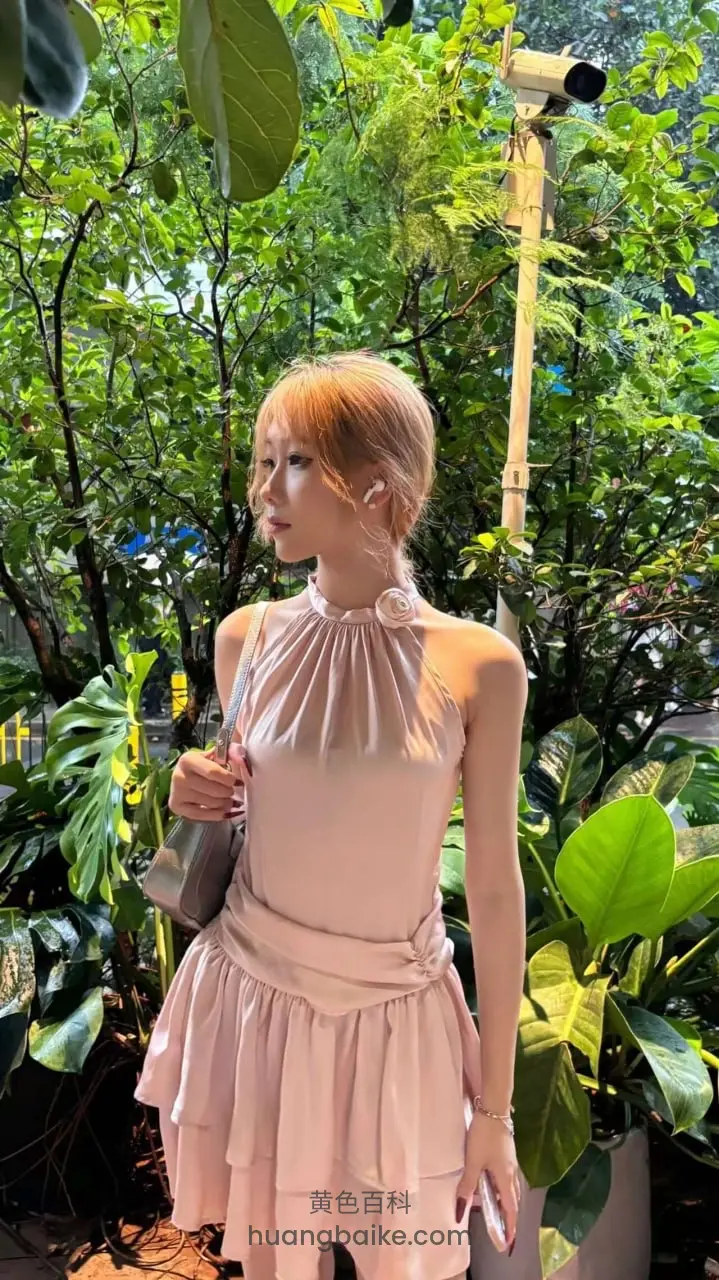 植物园里侧身站立，手拿手机