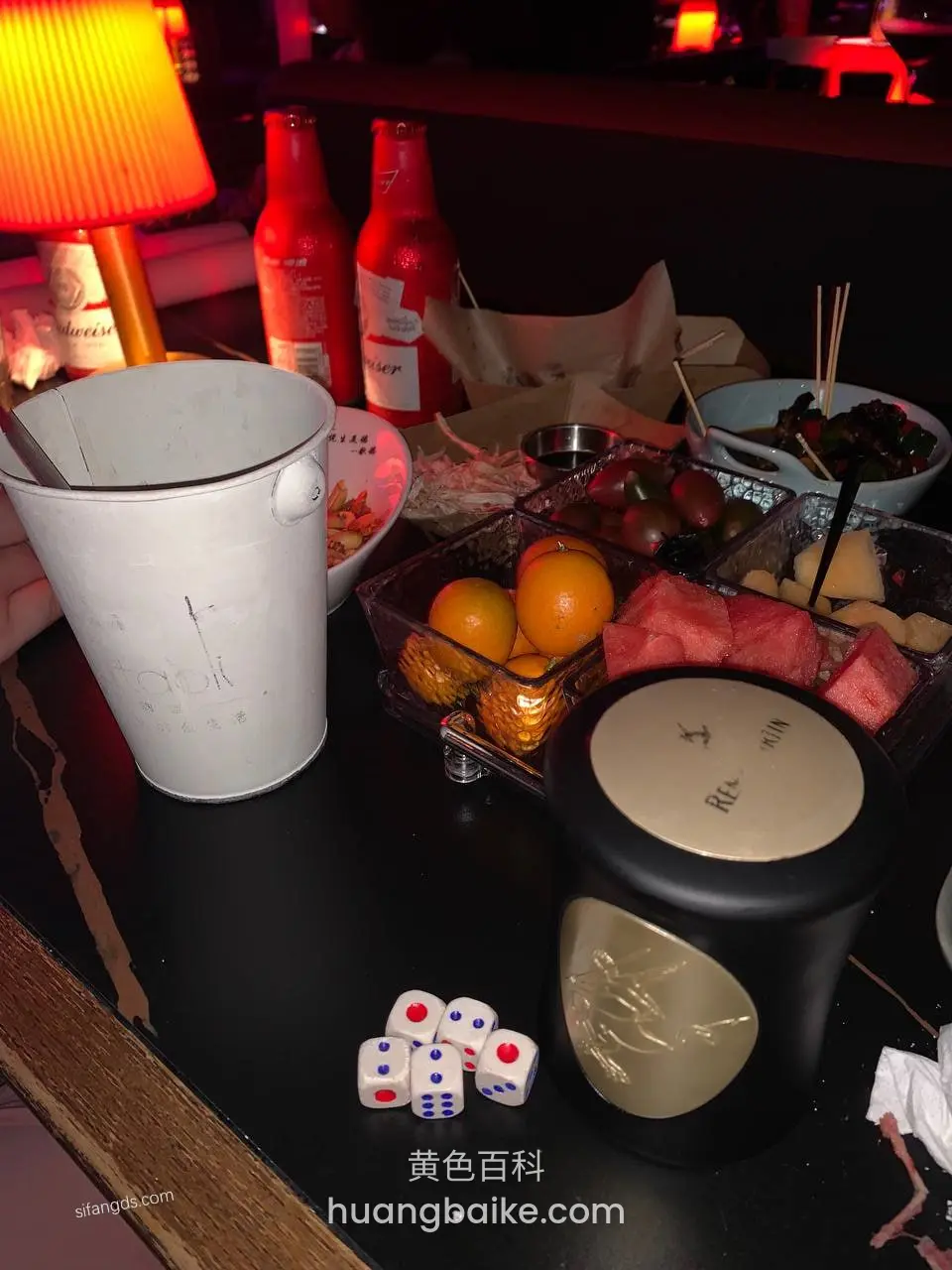黑桌上的冰桶水果和骰子
