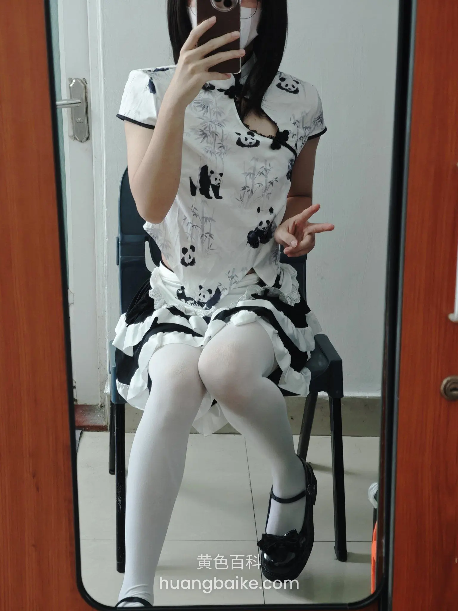 镜子前坐椅子上穿熊猫旗袍，举手机比剪刀手