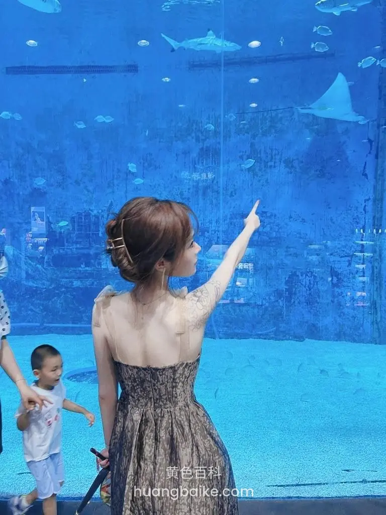 水族馆里，举手指向上方大鱼缸