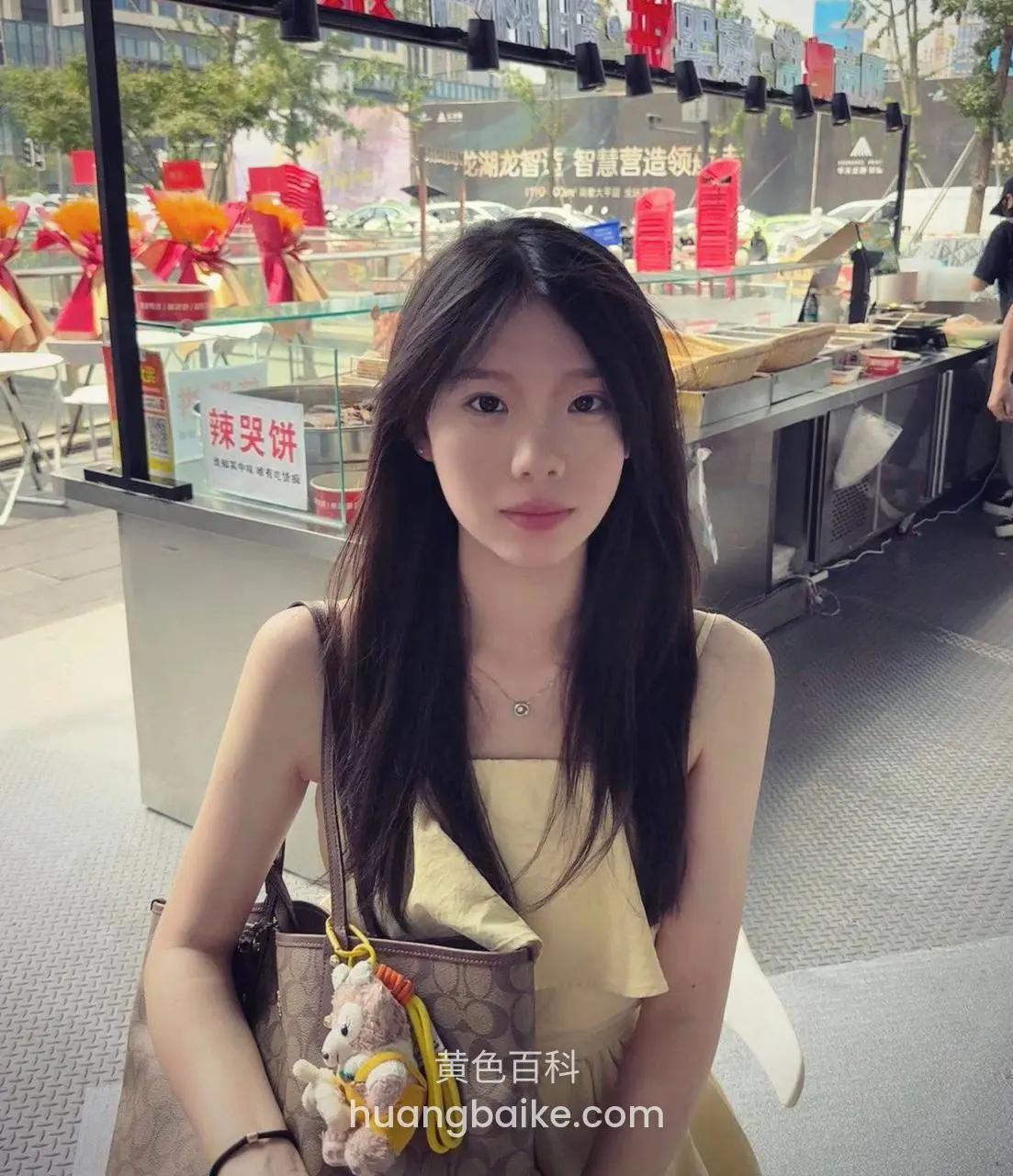 小吃摊前回头看镜头，身后招牌辣哭饼