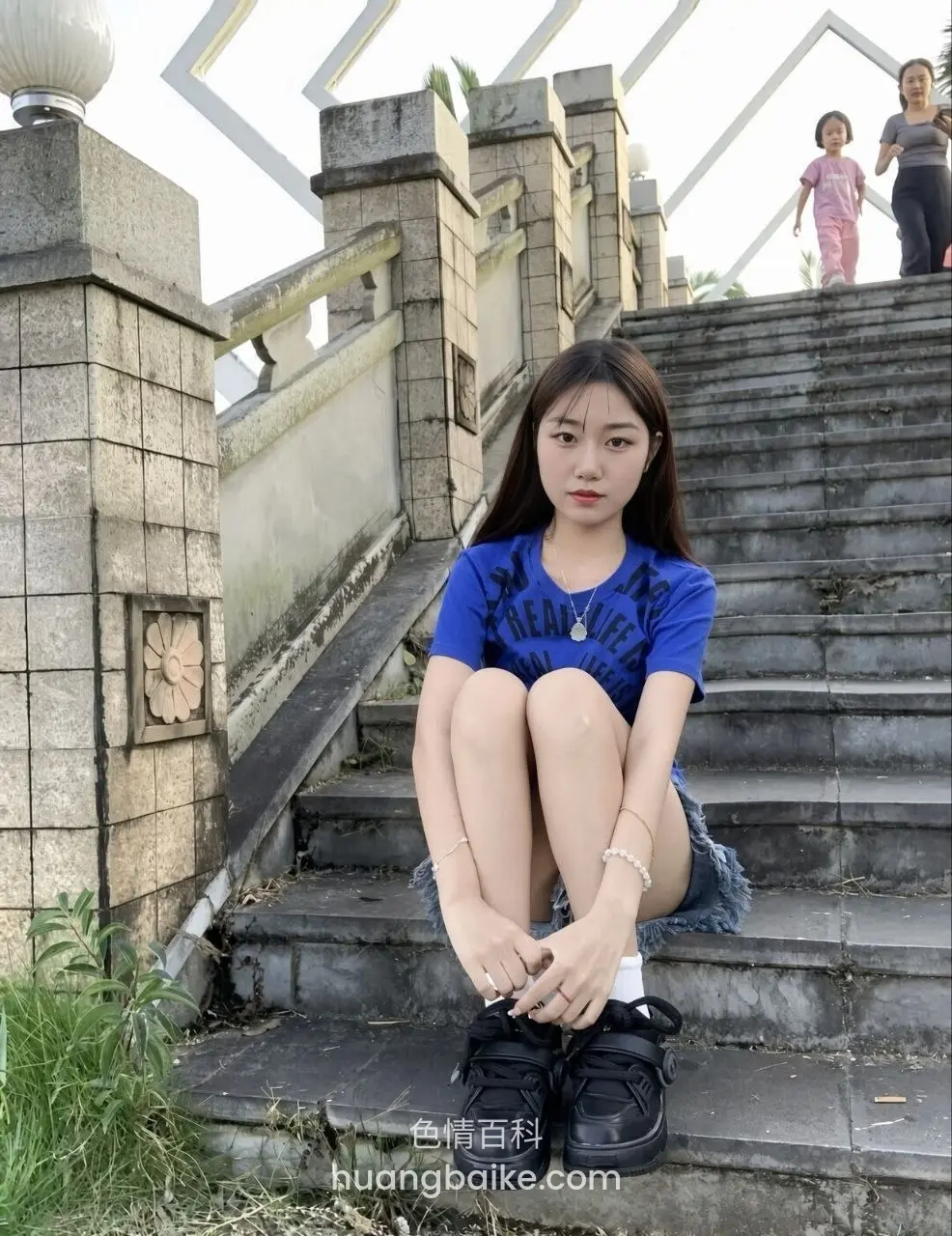 台阶上坐着抱膝，背景有行人走楼梯