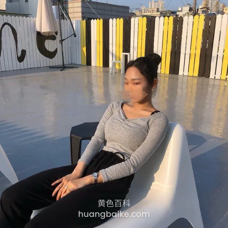 屋顶露台白椅子上坐着抽烟，身后彩色围栏和建筑