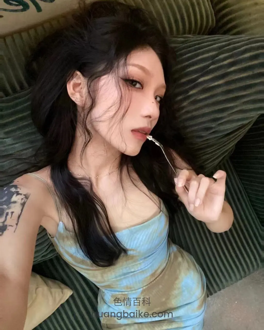 沙发上侧躺吃东西，身后绿沙发和抱枕