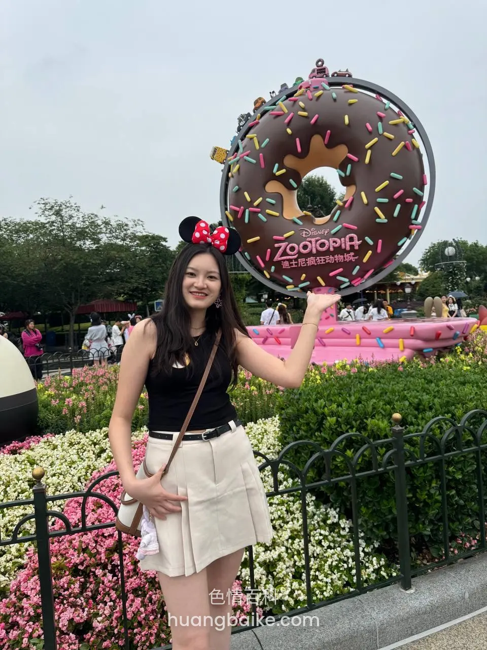 迪士尼巨型甜甜圈雕塑前右手比心，Zoopia 招牌在后