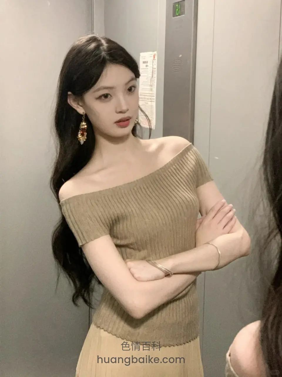 电梯里手臂交叉站立，身后有张贴纸