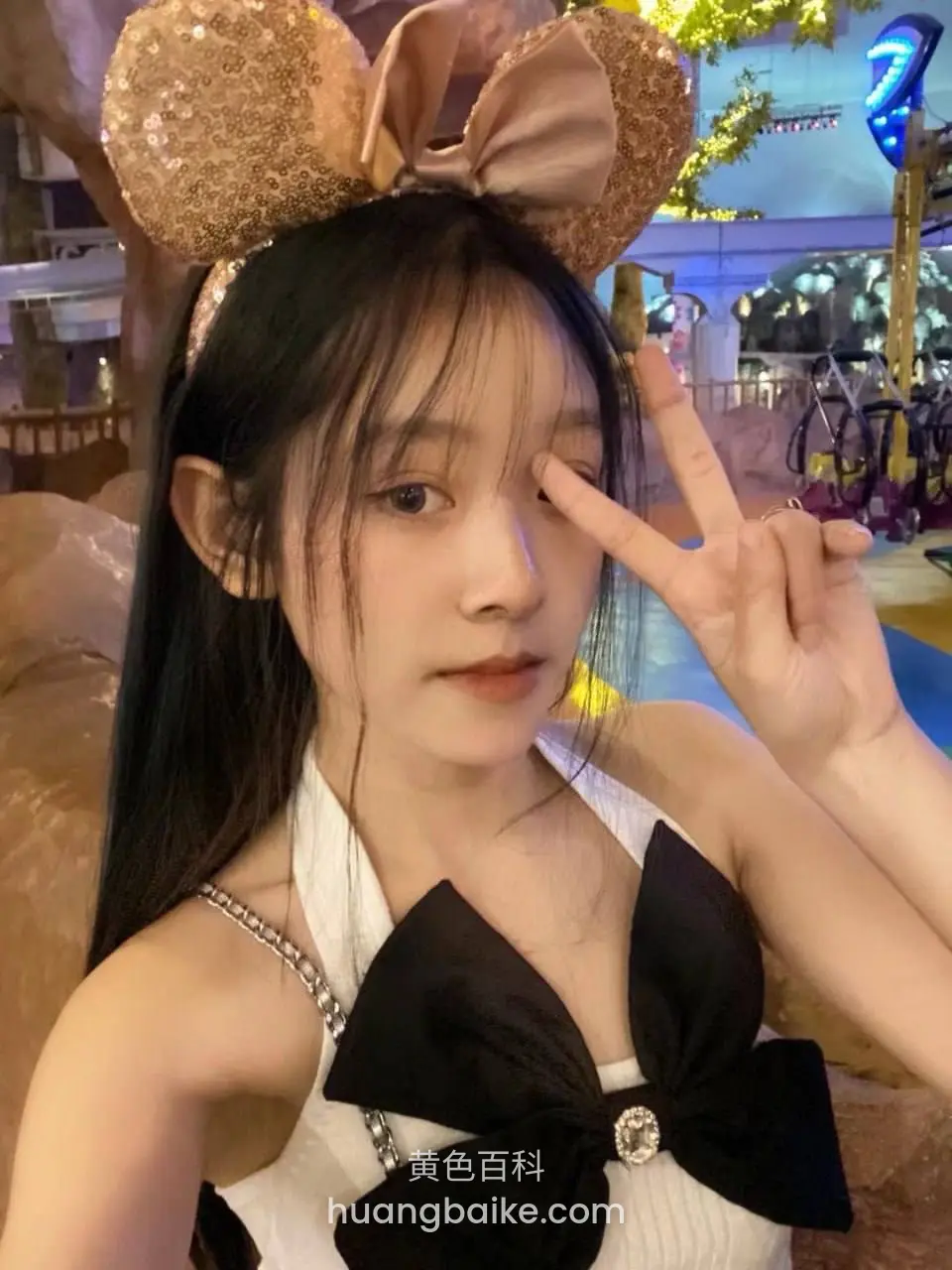主题乐园里举手比剪刀手，戴着米妮耳朵