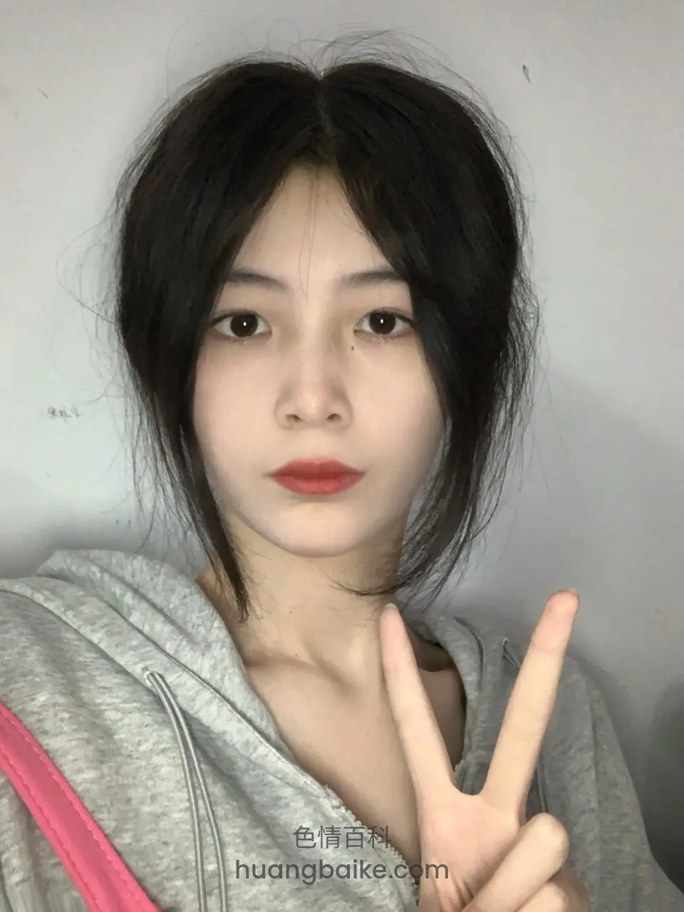 对着镜头比剪刀手，灰色卫衣
