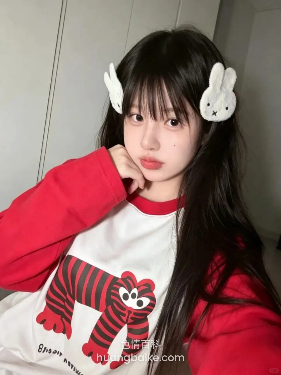 红白衣服手托下巴，身后是门