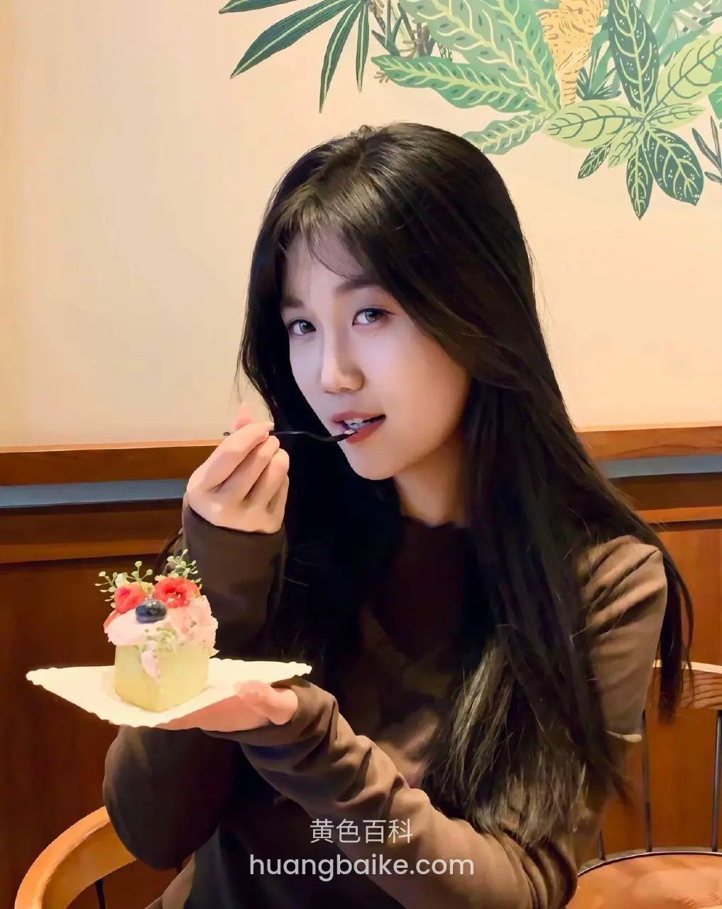 手拿小蛋糕吃一口，桌上放着叉子