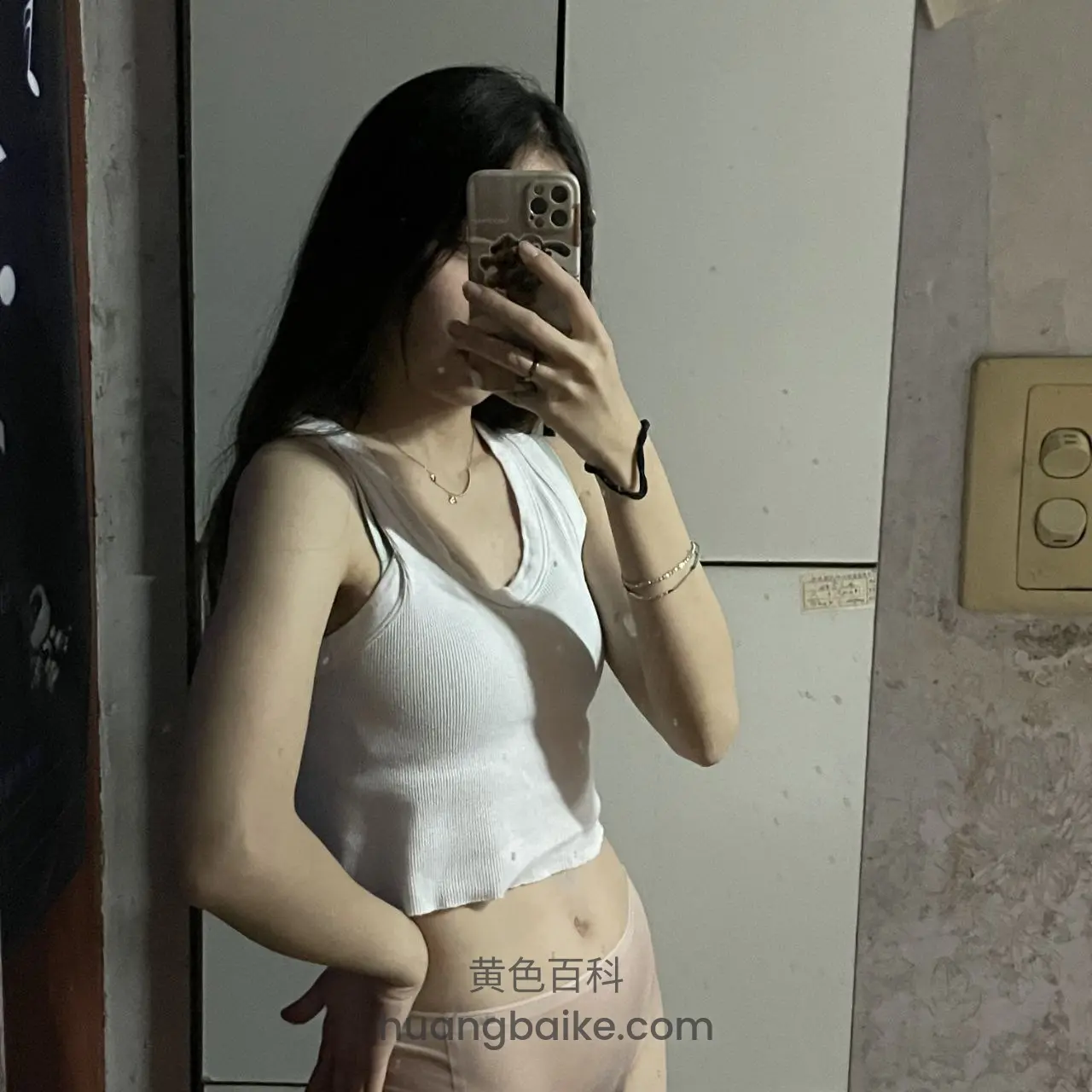 墙边举手机自拍，另一手叉腰