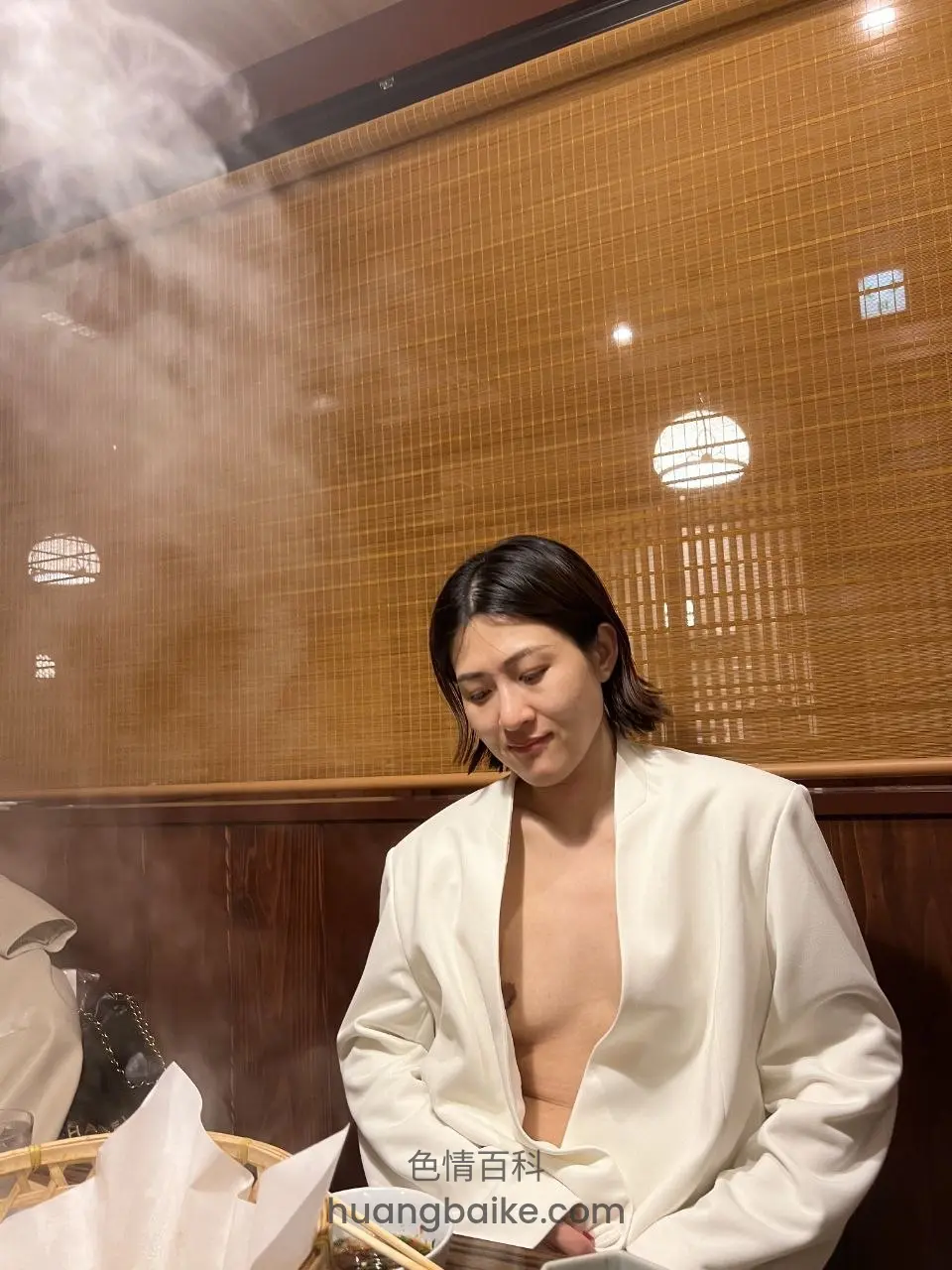 餐厅里低头看菜单，身后竹帘和蒸汽