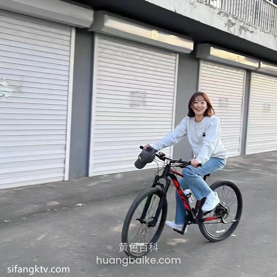 路边卷帘门前骑黑色红车，双手握把