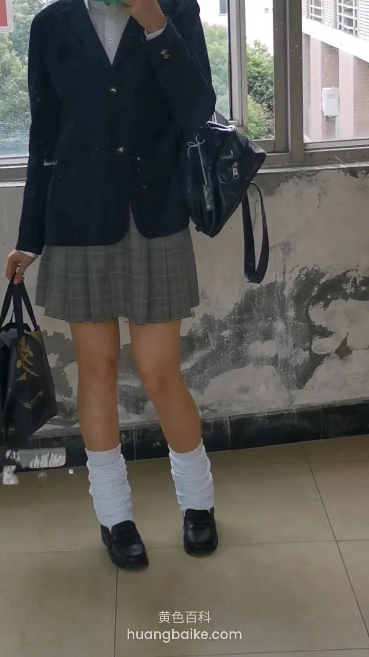 教学楼前站姿，手拿购物袋和手机
