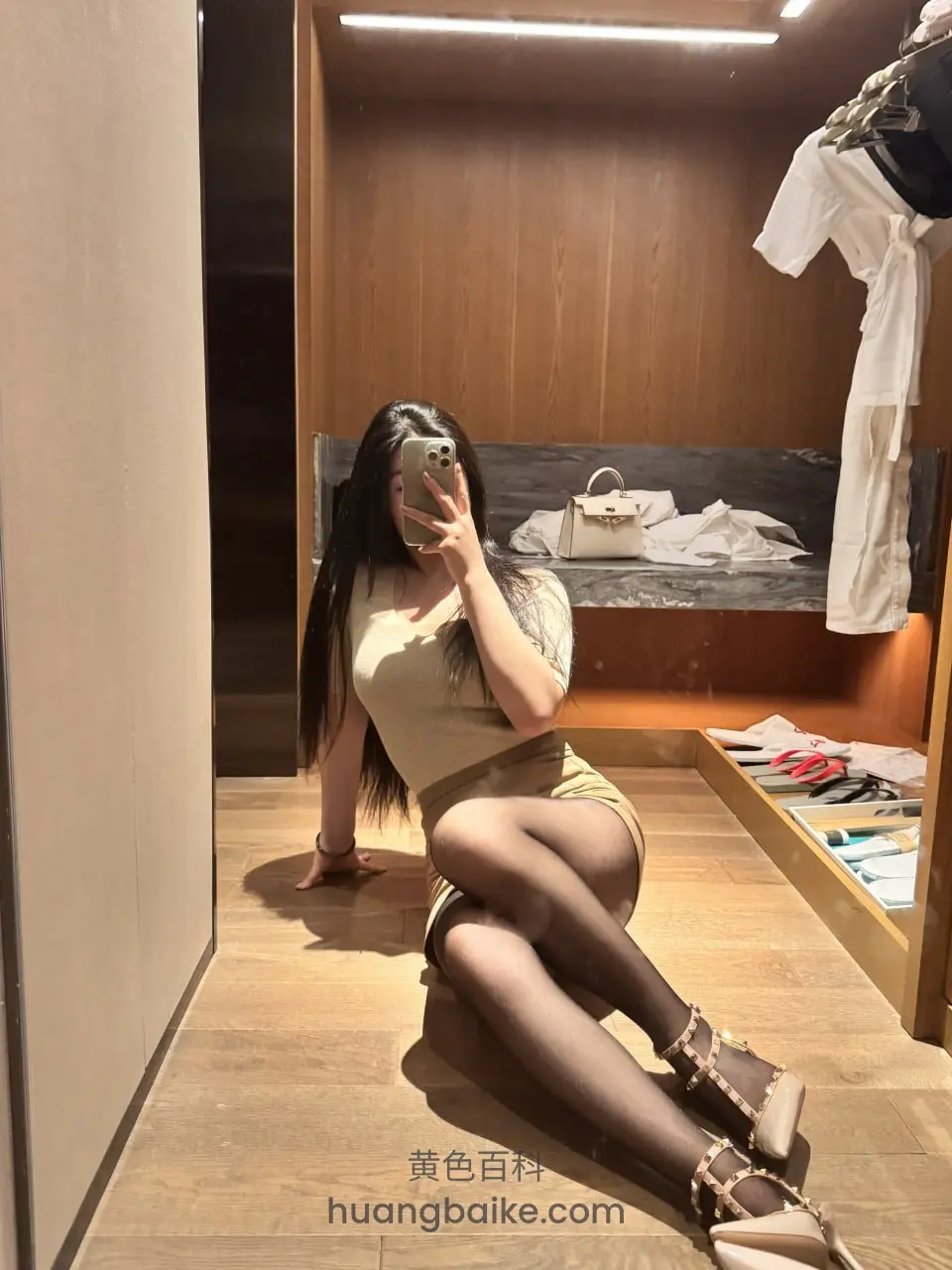 试衣间地板上坐着，手里拿着手机
