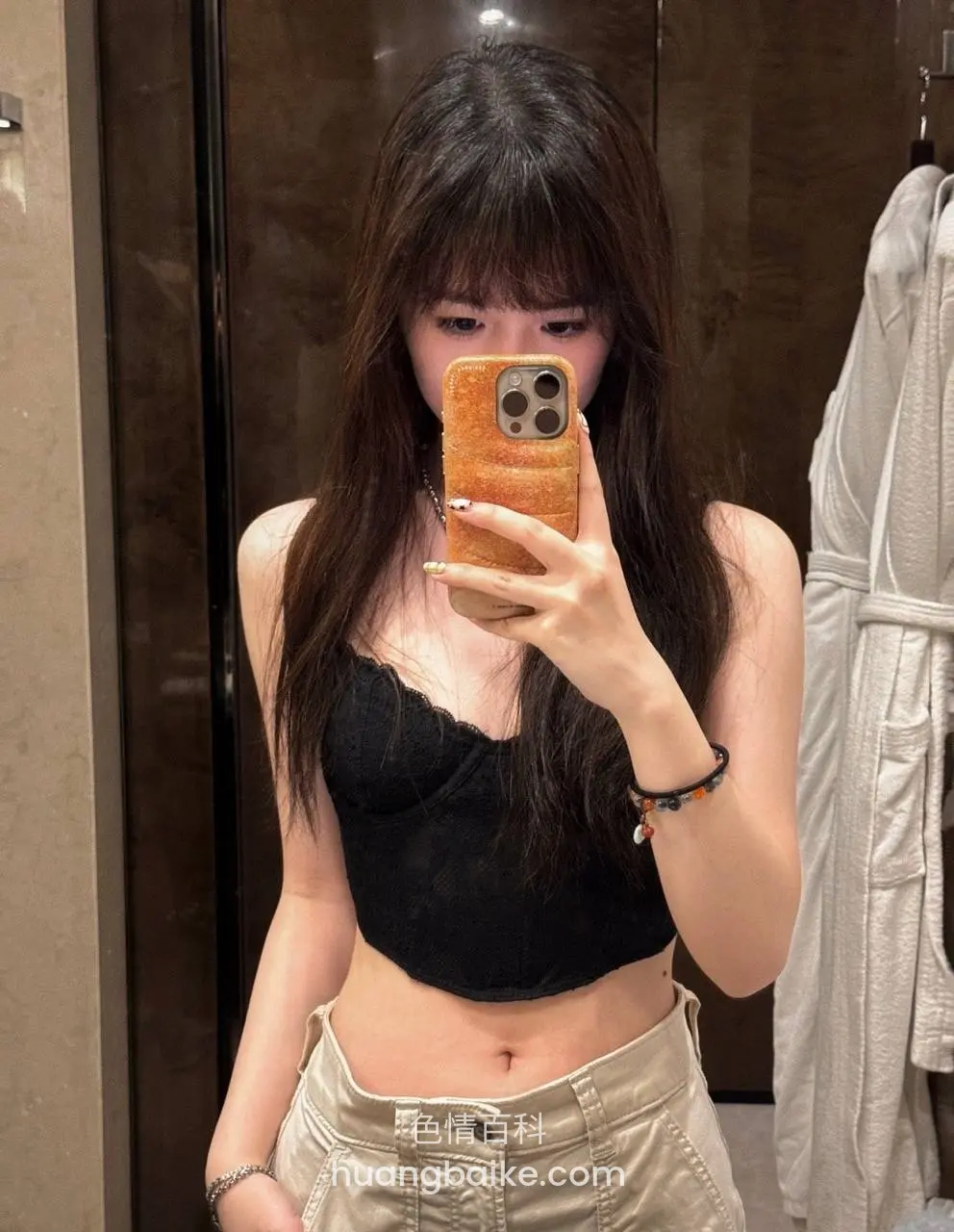 卫生间镜子前举橙色手机自拍，露腰