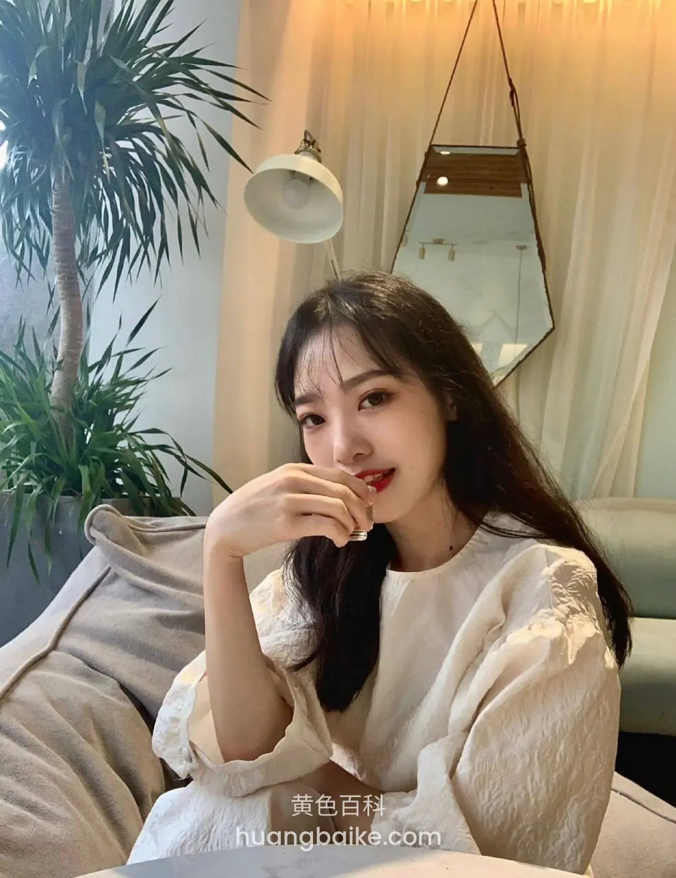 沙发上喝饮料，身后绿植和镜子