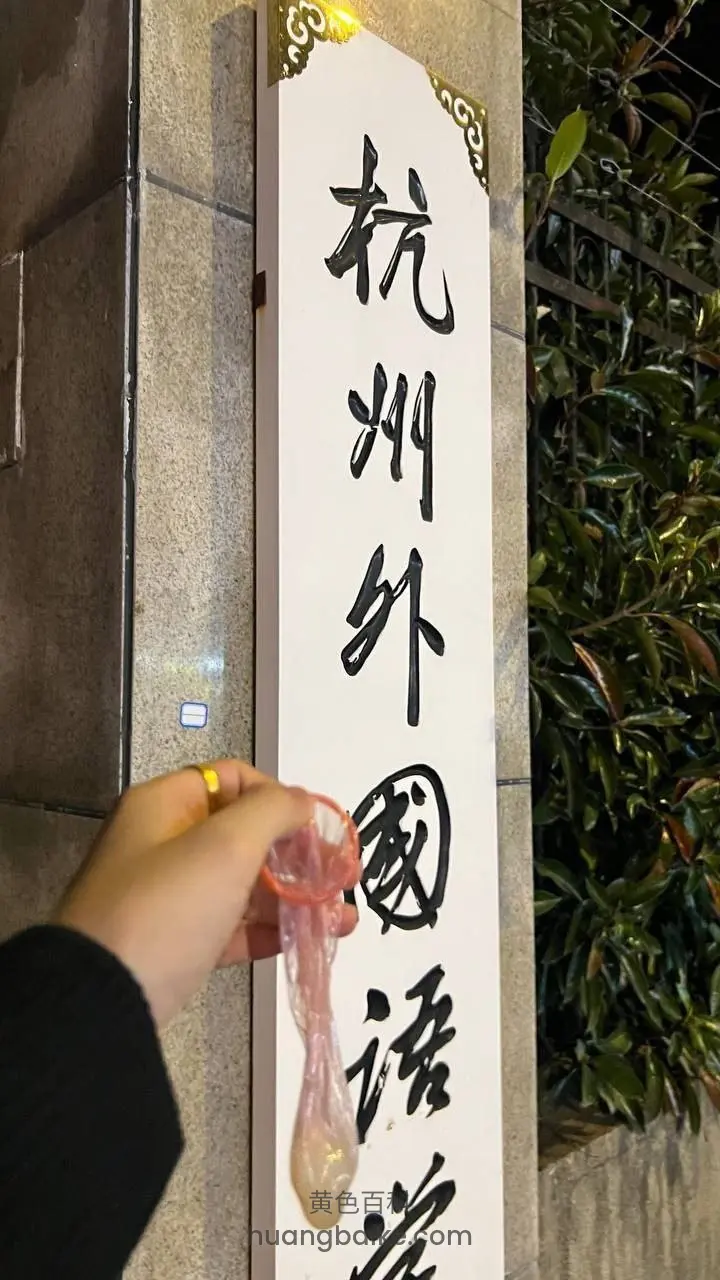 夜里竖幅招牌前，手里拿着用过的避孕套