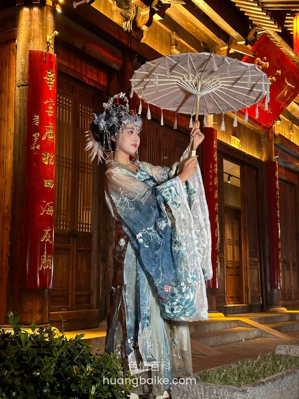 古镇门口举油纸伞，身后红灯笼对联