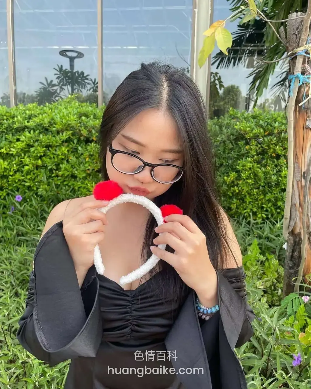 户外绿植前举白色红球头箍对着嘴
