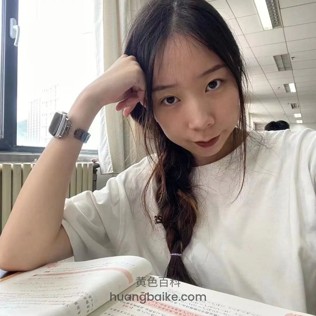 书桌上托腮看镜头，桌上摊开课本