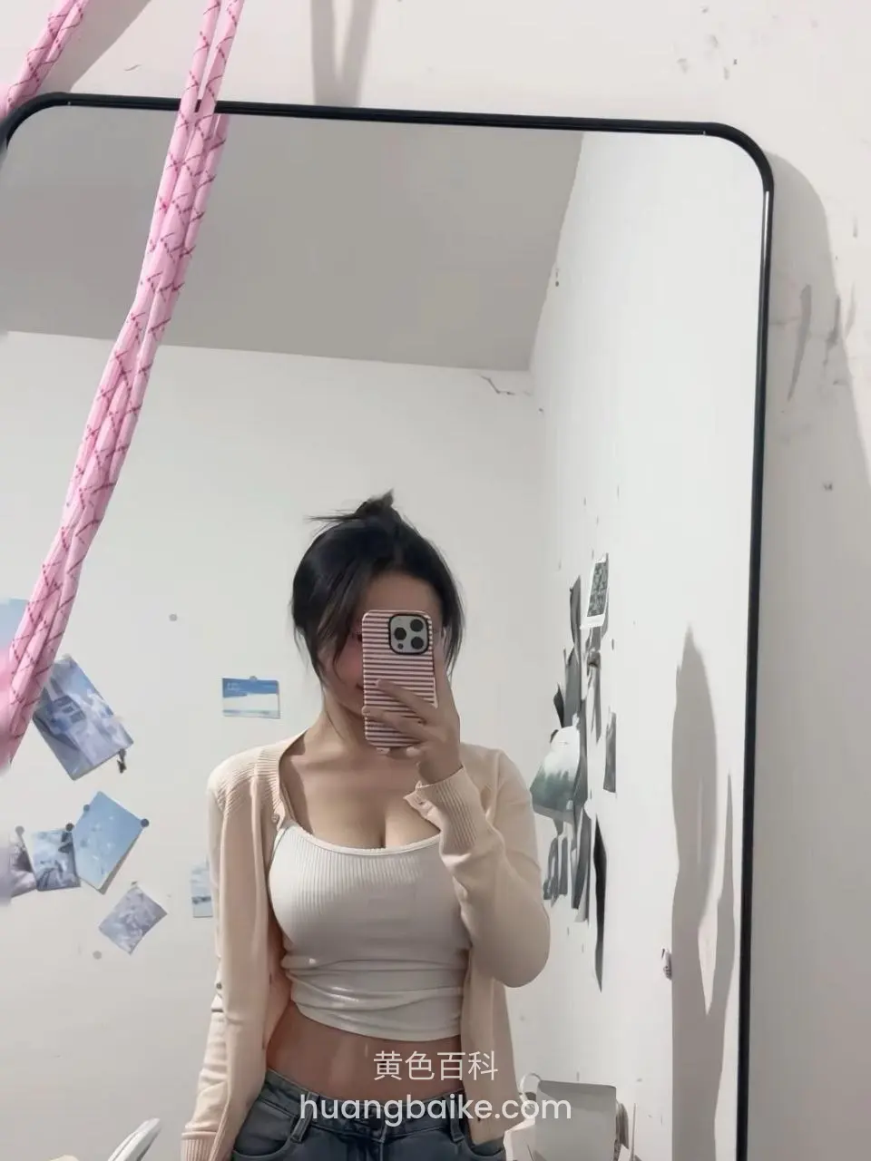 镜子前举手机自拍，身后墙上贴着照片
