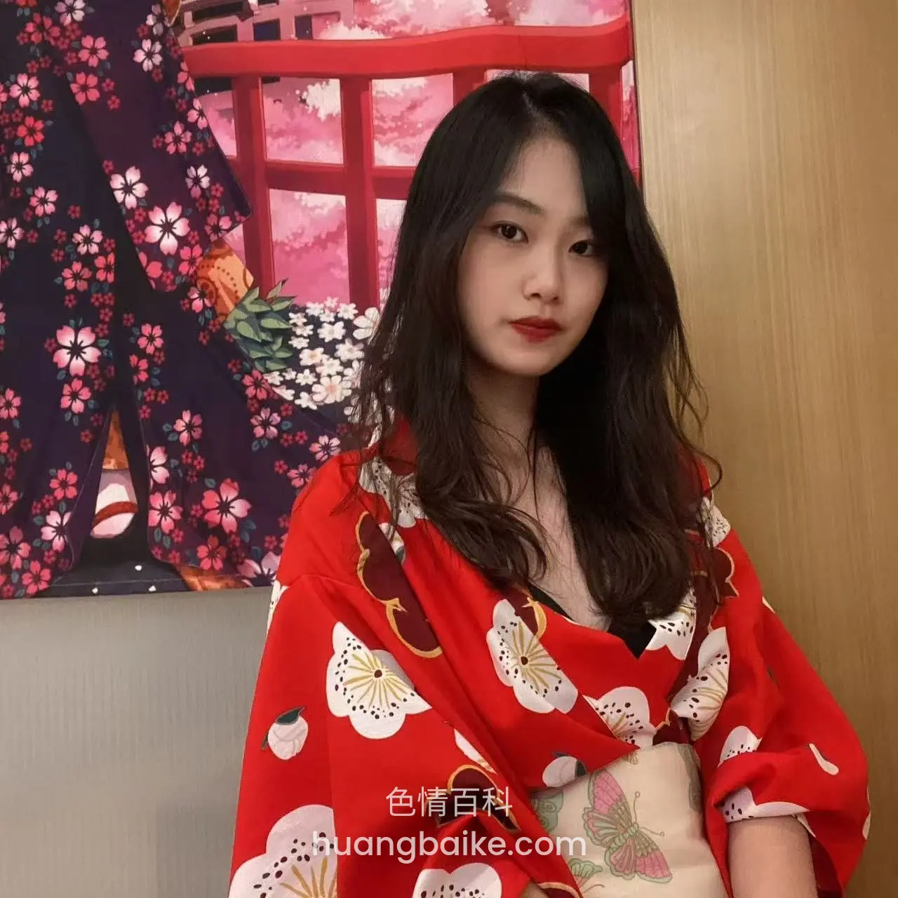 红衣服坐在墙边，身后是樱花图案屏风