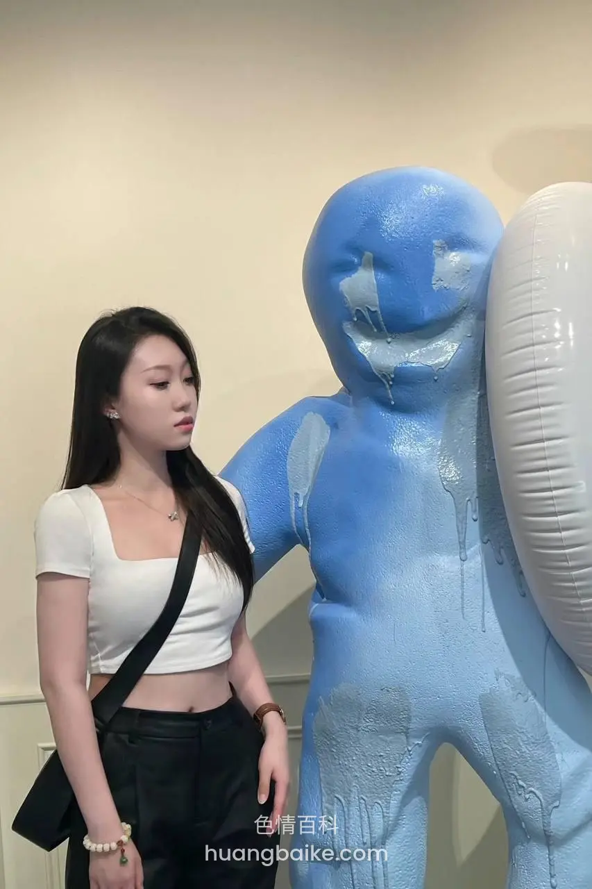 室内白墙前站着看蓝色雕塑