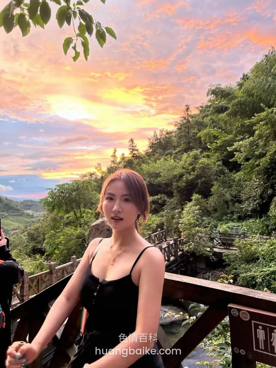木桥上扶栏杆看镜头，身后日落山谷