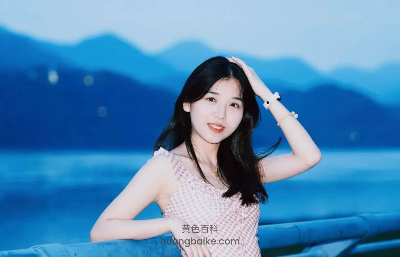 湖边栏杆上扶着头，身后是蓝色山景