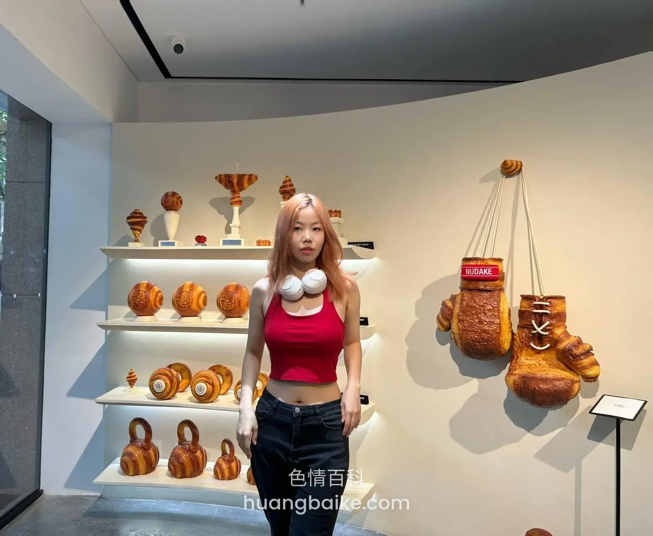 艺术展厅里走过，手里拿着白色胸部模型，墙上挂着面包雕塑