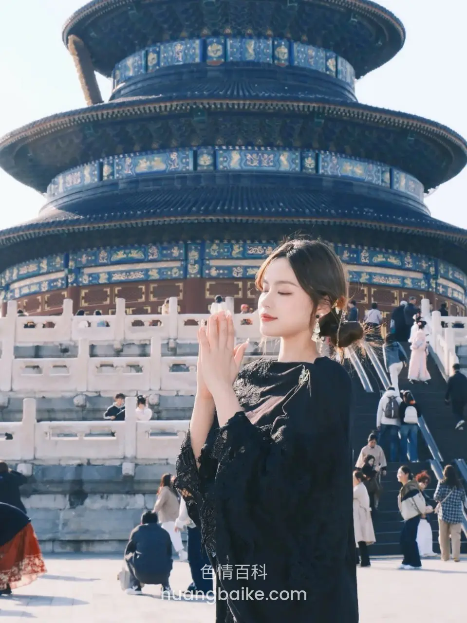 双手合十站在天坛前，镜头对着人群和台阶