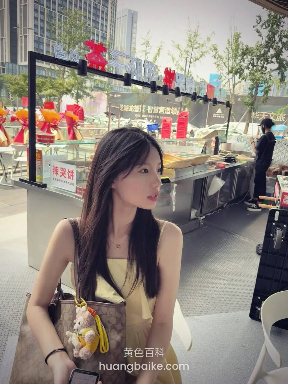 街边小吃摊前坐着，拿着手机看旁边
