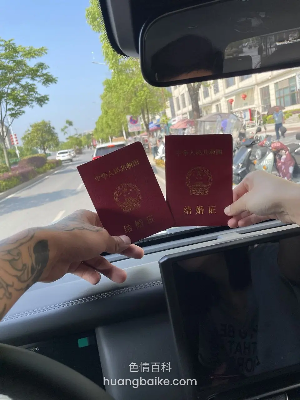 车里举着两本结婚证，镜头对着前方街道