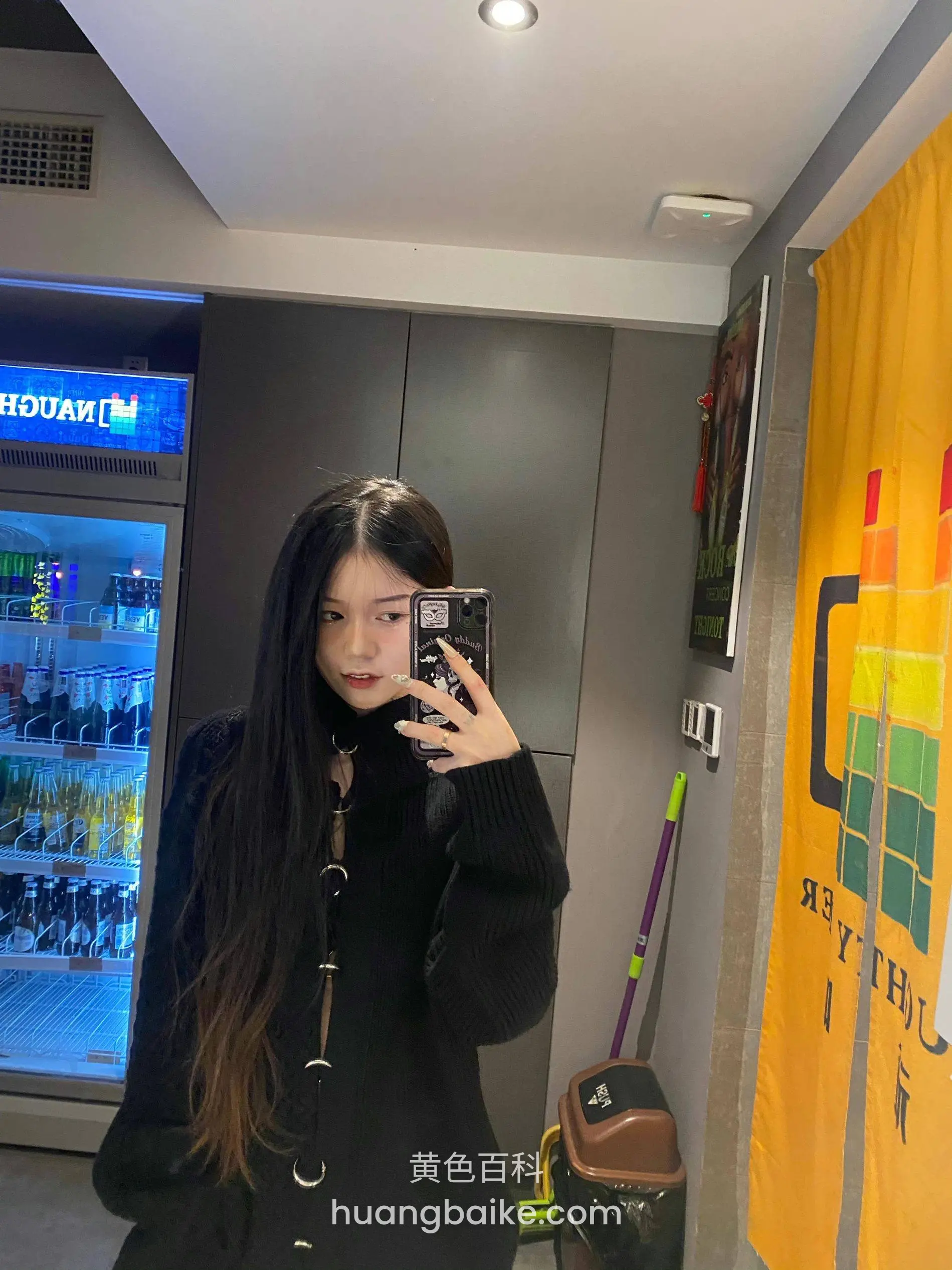 便利店里拿着手机，身后是冰柜