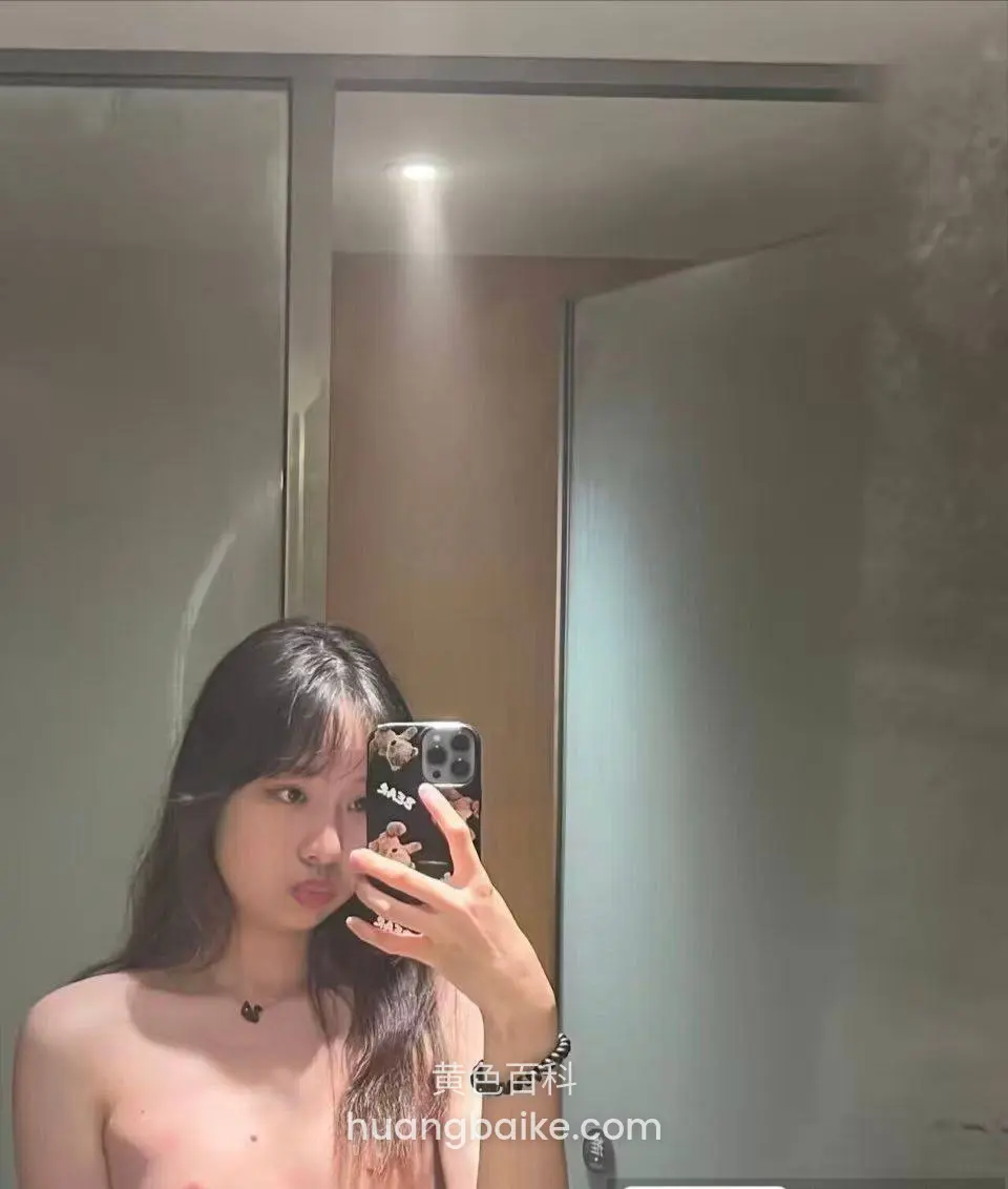 浴室镜子前自拍，手机举在脸旁，门后有灯光