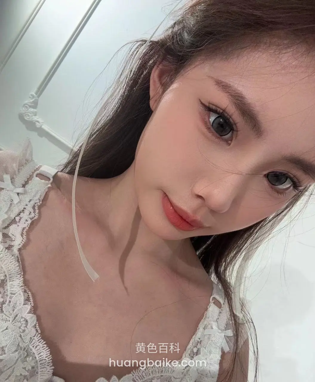 室内白墙前低头自拍，白色蕾丝上衣