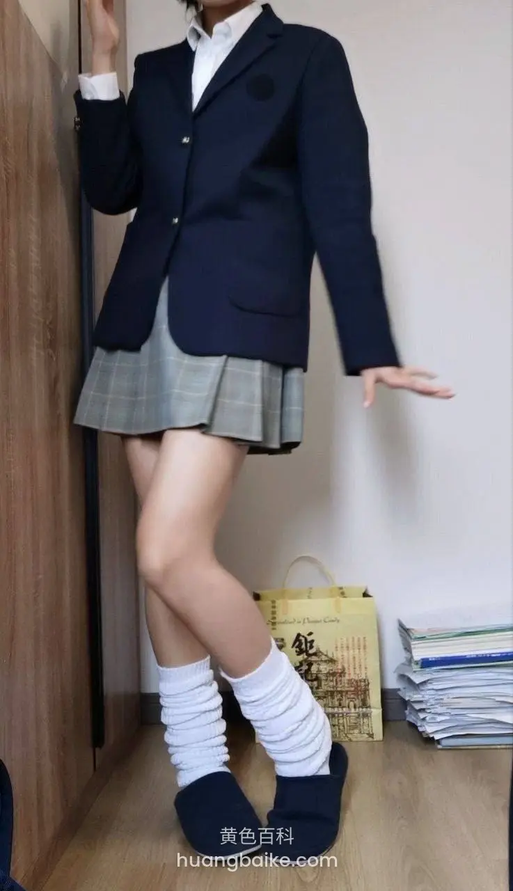 木门边站立，左手扶门右手伸出，校服下摆露白袜和拖鞋