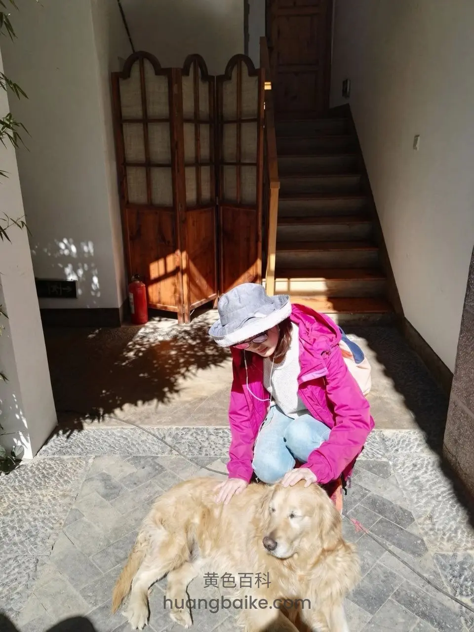 蹲在玄关石砖地抚摸金毛犬，身后木屏风和楼梯