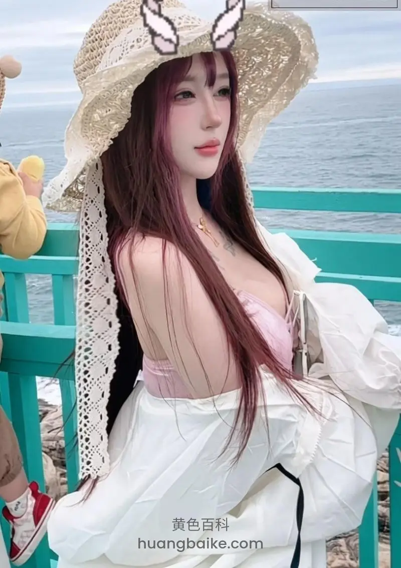 海边栏杆前回头看，戴兔耳草帽身后大海