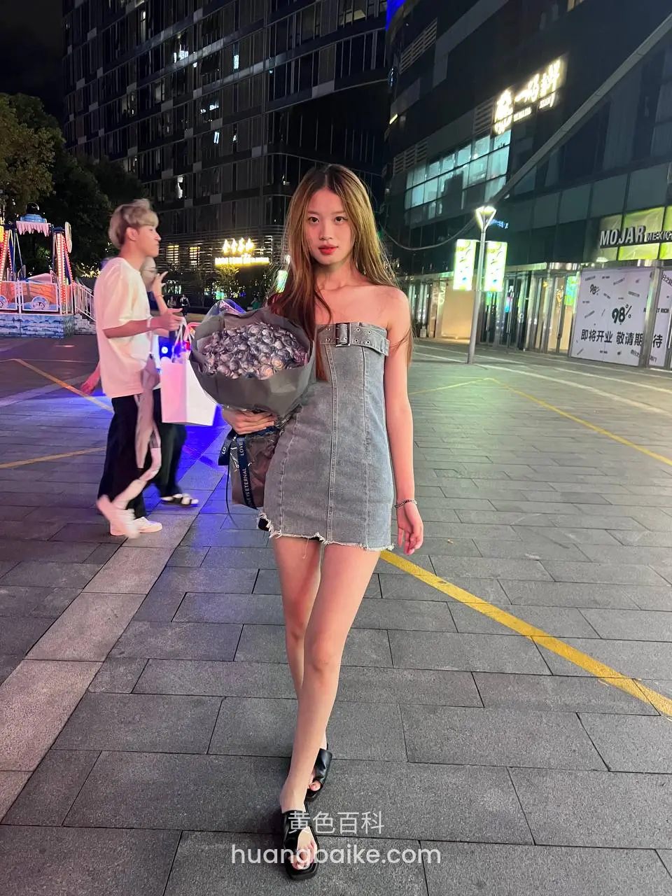 手里拿着花束，站在夜间街头