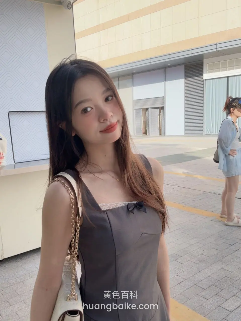 户外建筑前回头看镜头，肩背白色链条包