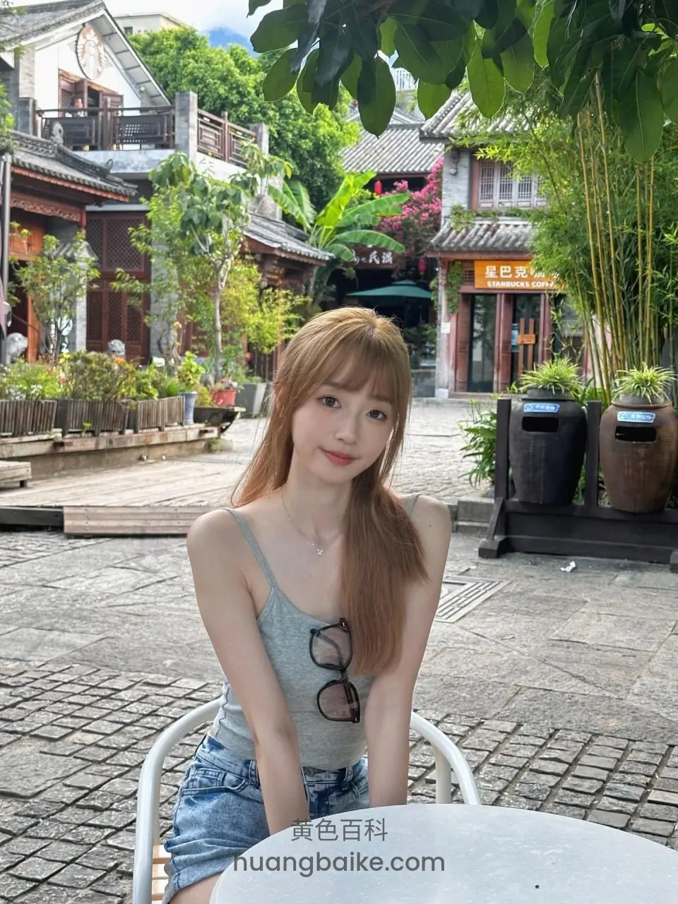 古镇街头白桌前坐着，身后是传统建筑和绿植