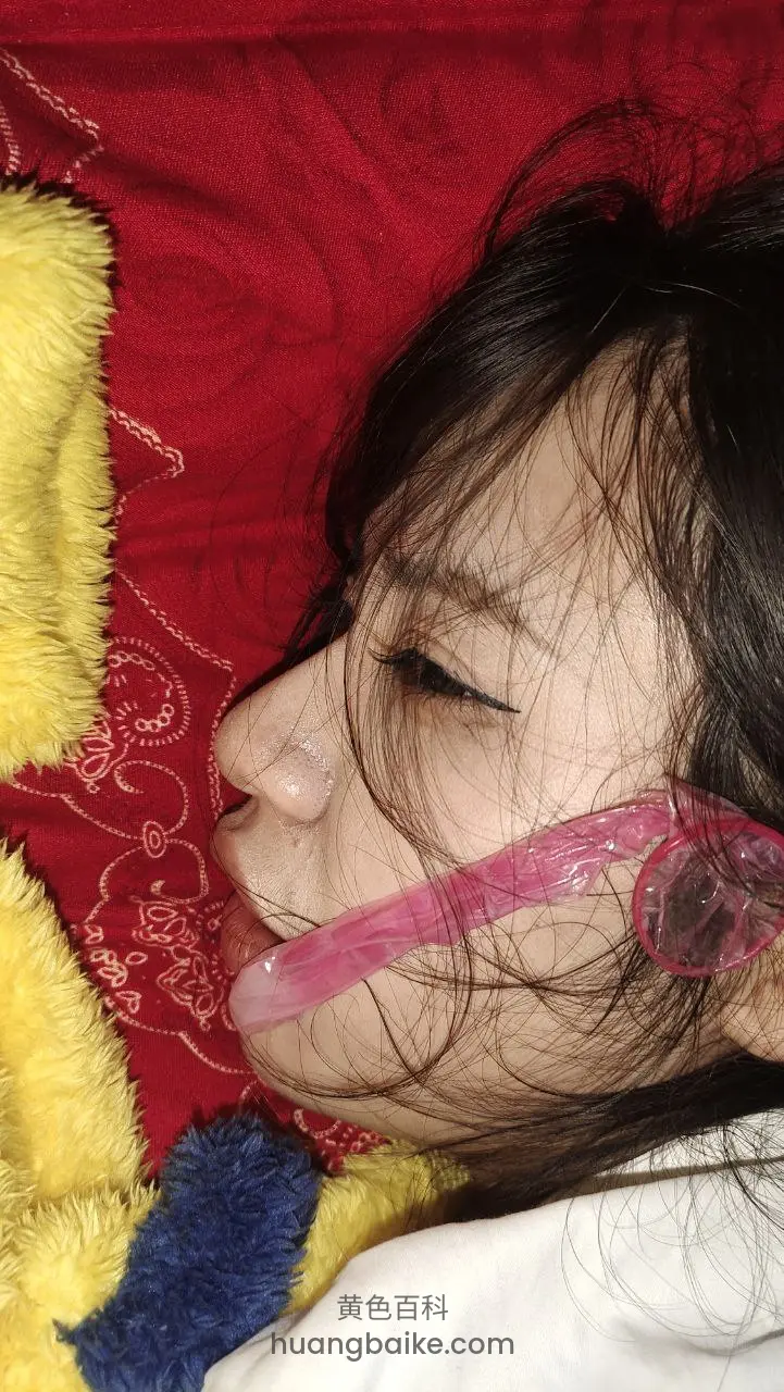 床上躺着侧脸，嘴里咬着粉色玩具