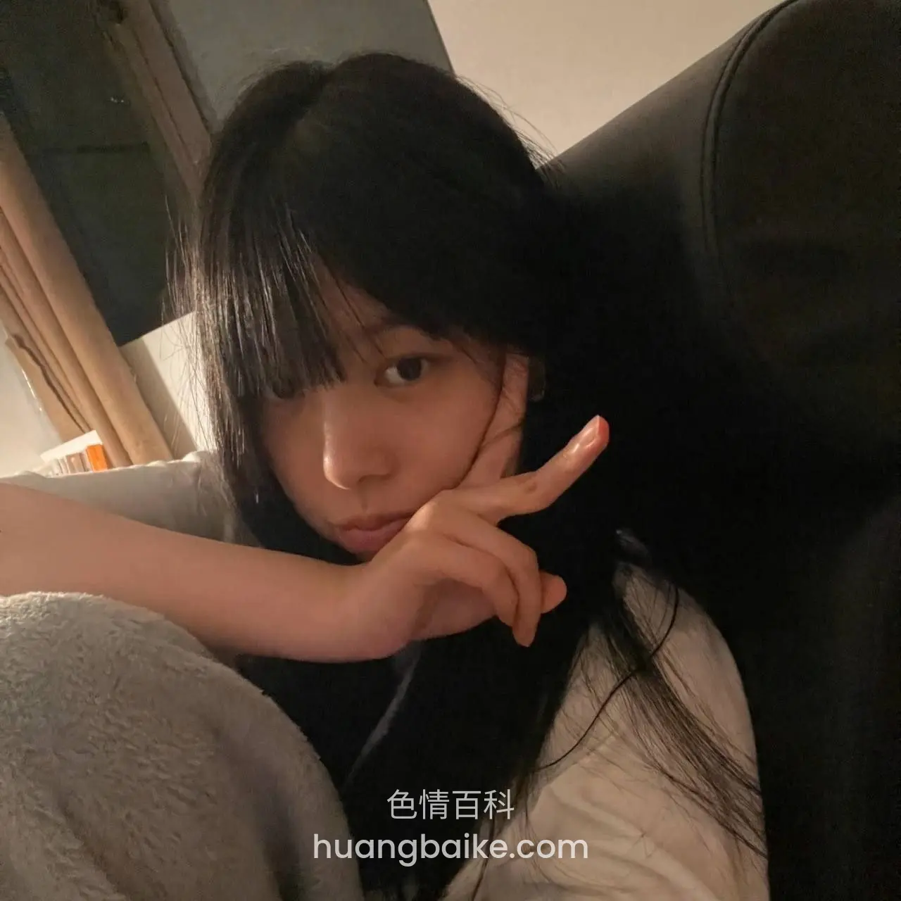 沙发上侧头看镜头，手指比V
