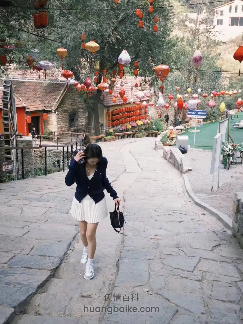 景区石板路上走着，身后挂满红灯笼