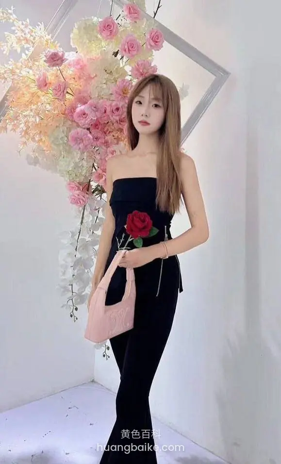 花墙前拿玫瑰和包站立